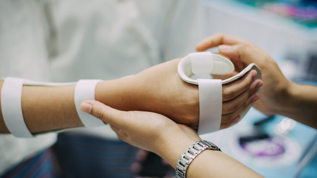 Hand occupational therapist making assistive device for immobilize patient hand. Splint service for hand injury rehabilitation of occupational therapy clinic.